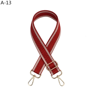 Macro detail of red and white herringbone knit bag strap with gold metal lobster clasps