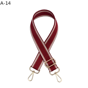 Close-up of red and white woven adjustable shoulder strap with gold-tone hooks