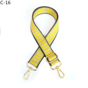 Detail of adjustable yellow and beige woven bag strap with golden metal snap hooks