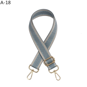Detail of grey and light blue herringbone woven bag strap with golden lobster claws