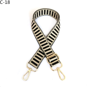 Detail of striped black and beige replacement bag strap with golden metal swivel hooks