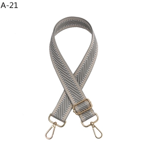 Close-up of adjustable grey geometric woven bag strap with gold metal lobster clasps