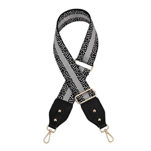 Macro shot of geometric black and white bag strap with gold rivets and metallic hooks