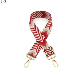 Detail of adjustable red and gold wave pattern shoulder strap with gold metal hooks