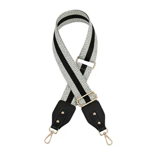 Adjustable woven purse strap with black leather ends, gold studs, and metal hooks