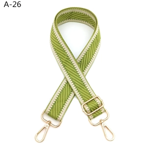 Adjustable green and beige woven shoulder strap with gold metal hooks and hardware