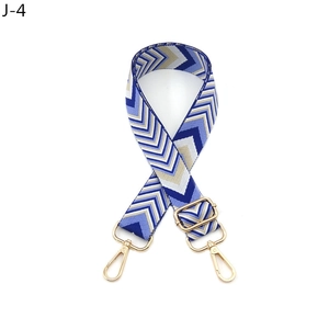 Close-up of geometric V-pattern wide shoulder strap with gold metal swivel hooks and buckle