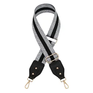 Adjustable shoulder strap with gray dotted pattern, black leather ends and gold metal rivets