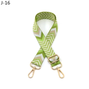 Close-up of adjustable woven shoulder strap with green chevron pattern and gold lobster clips