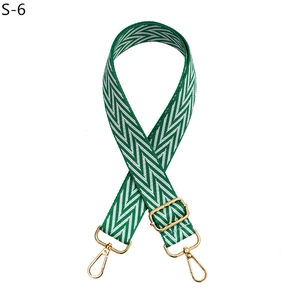 Close-up of adjustable woven bag strap with green wave pattern and gold metal hooks