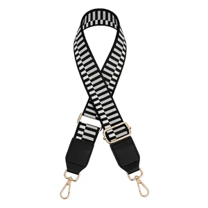 Detail view of adjustable black and grey striped bag strap with gold metal buckles