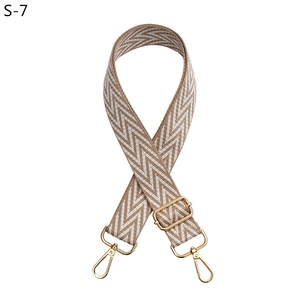 Close-up of adjustable woven bag strap with herringbone pattern and gold swivel hooks