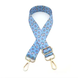 Detail of light blue floral canvas strap with golden lobster clasps and metal slider