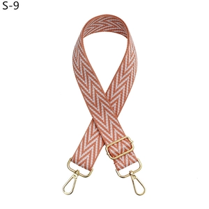 Detail of adjustable orange and white herringbone bag strap with gold metal hooks