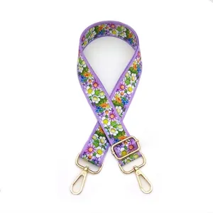 Close-up of lavender floral bag strap with small daisies and gold metal swivel hooks