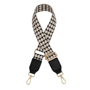 Detail of black and white houndstooth woven shoulder strap with gold metal hooks