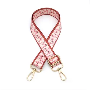 Close-up of pink cherry blossom patterned bag strap with golden metal swivel hooks