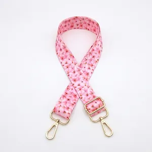 Close-up of pink floral pattern bag strap with golden metal lobster clasps and adjuster