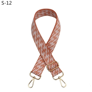 Detail of adjustable woven bag strap in orange and white with gold metal buckles
