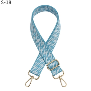 Detail of blue and white geometric woven bag strap with adjustable gold lobster buckles
