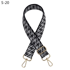 Close-up of adjustable woven bag strap with black and white geometric jacquard and gold hardware