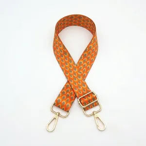 Detail of adjustable wide purse strap with orange fish scale pattern and gold hardware