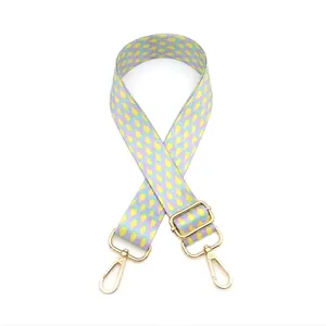 Close-up of adjustable fabric bag strap with colorful scale pattern and gold hardware