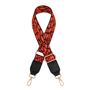 Detail of red and black leopard print woven bag strap with golden metal hardware clips