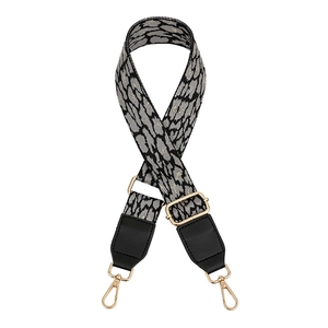 Close-up of leopard pattern woven bag strap with black leather ends and gold metal clips