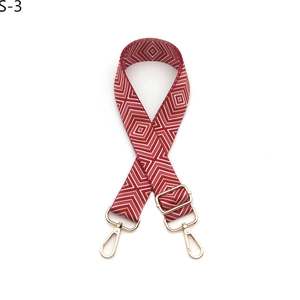 Detail view of red and white geometric woven guitar bag strap with gold metal lobster clasps