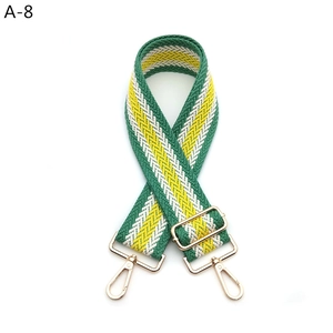 Detail of adjustable wide woven bag strap with green herringbone pattern and gold hooks