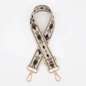 Close-up of geometric jacquard woven strap with golden lobster clasps and metal buckle