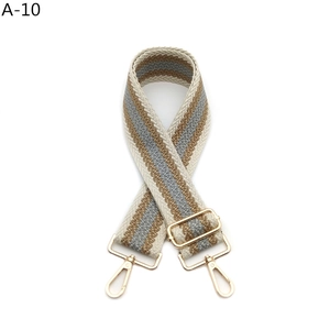 Close-up of thickened woven bag strap with golden metal lobster clasps and striped texture
