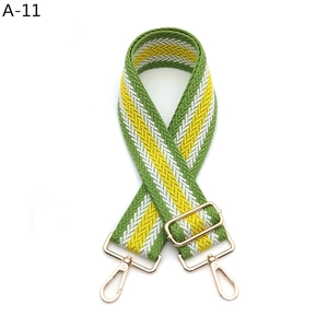 Close-up of green and white woven shoulder strap with adjustable golden metal buckles
