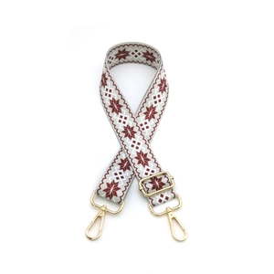 Detail of adjustable gray strap with red and white snowflake patterns and gold metal hooks