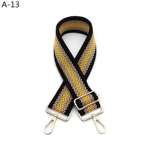 Macro detail of adjustable wide woven bag strap with ethnic pattern and gold buckles