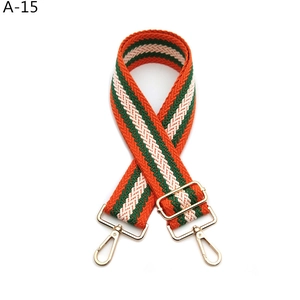 Detailed view of the wide woven strap with orange, green, and white patterns and gold hooks