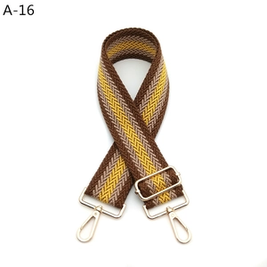 Detail of adjustable woven bag strap with golden alloy hooks and wave pattern design