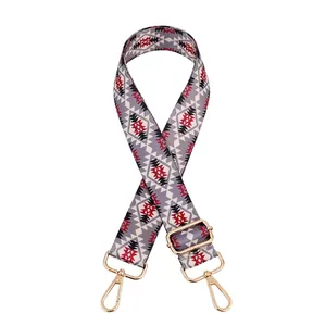 Close-up of ethnic grey bag strap with red geometric patterns and gold metal buckles