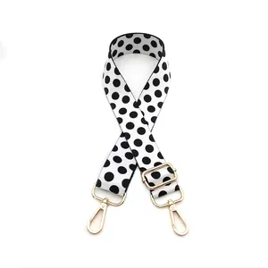 Close-up of black and white polka dot bag strap with gold metal adjustable buckle