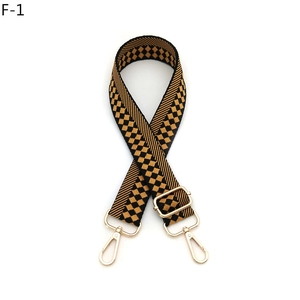 Detail of adjustable black and tan geometric checkerboard strap with gold metal hooks