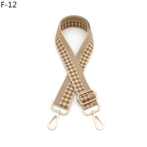 Macro detail of checkered beige and brown woven bag strap with golden metal clasps