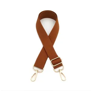 Detail of adjustable thick dark brown nylon bag strap with gold metal lobster clasps