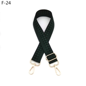 Detail view of adjustable checkered bag strap in dark green with gold metal lobster clasps