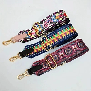 Close-up of three woven wide bag straps with bohemian patterns and gold metal buckles