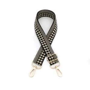 Detail of adjustable checkerboard woven shoulder strap with gold metal lobster clasps