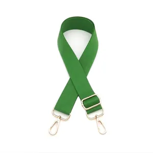 Detail view of grass green bag strap with gold lobster hooks and metal slider buckle