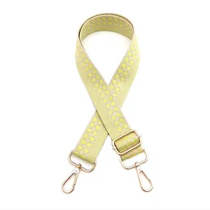 Detail of adjustable green and beige checkered guitar strap with gold lobster clasps