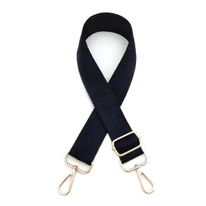 Detail of adjustable blue and black checkered bag strap with light gold metal swivel hooks