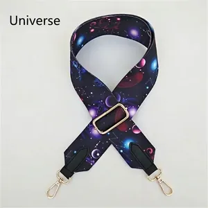 Close-up of a wide adjustable bag strap with universe space patterns and gold hardware